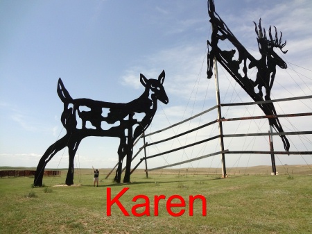 Karen Duquette under the sculpture entitled Deer Crossing