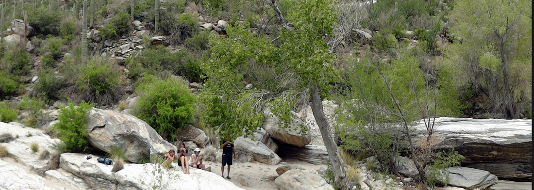 people swimming under a very small waterfall