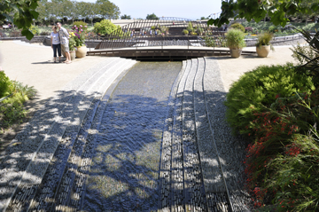 the water flows downward and under a small bridge.