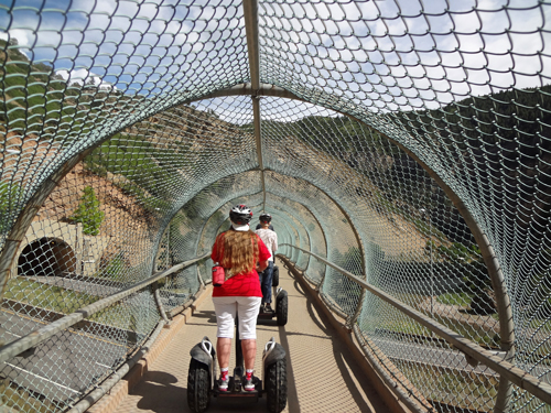 Karen Duquette riding a Segway through a bridge