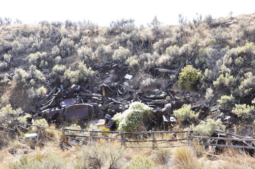 A pile of very old cars in a junk yard area