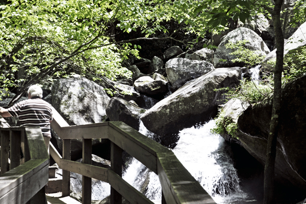 Lee Duquette on a bridge overlook a small cascade of water