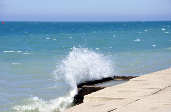 Karen Duquette photographs the waves breaking over the seawall