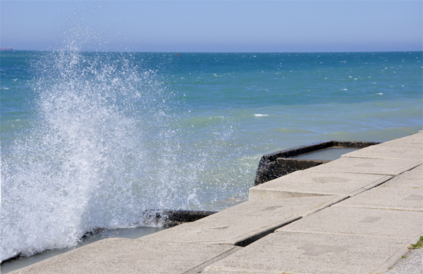 Karen Duquette photographs the waves breaking over the seawall