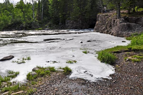 Karen Duquette feels the foam in see the foam swirling as the force of the river hits Lake Superior.