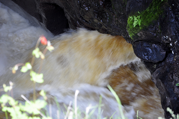 water that is flowing rapidly into the pothole below