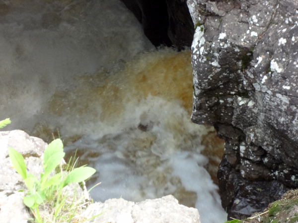 water that is flowing rapidly into the pothole below