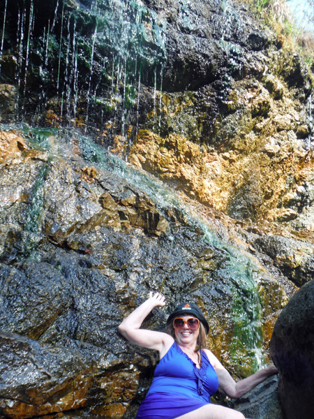 The hot water sprinkles down the cliffs like a gentle waterfall as Karen enjoys the experience.