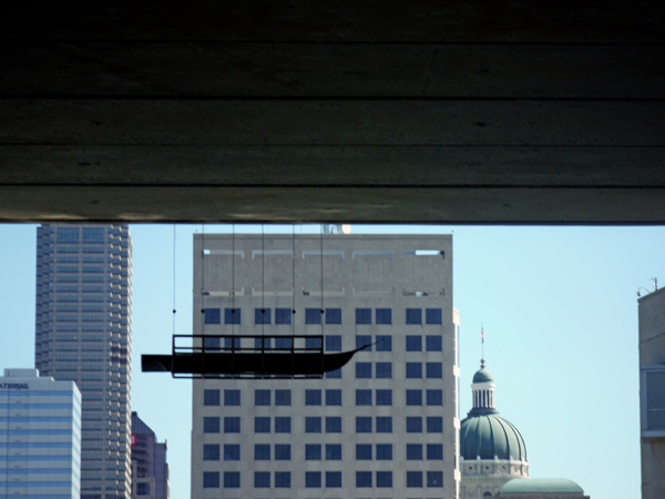 A small boat hanging from the underside of a bridge