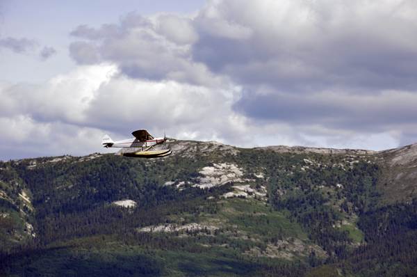 a float plane flying over the mountain