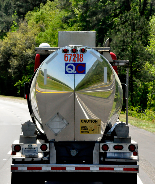 A distorted image reflected in the back of a shiny truck