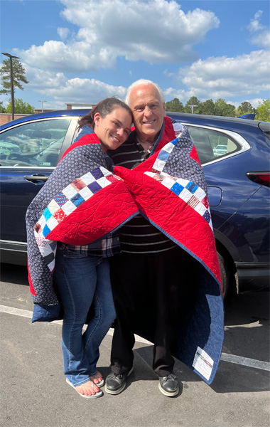 Lee Duquette with his grandaughter and the Quilt