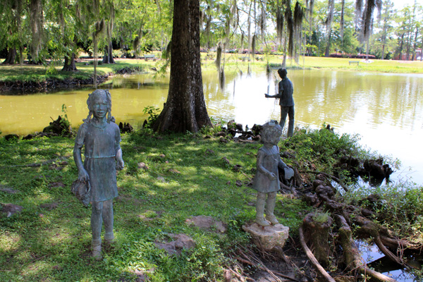Statues of 3 children playing by the pond