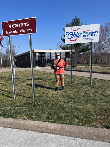 Karen Duquette with the Veterans Memorial Highway Sign