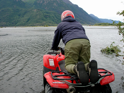 the guide kneeling & driving across the deep river