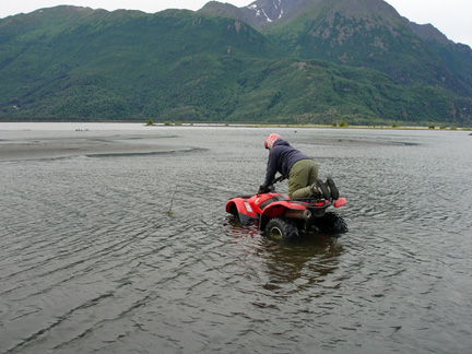 the guide kneeling & driving across the deep river