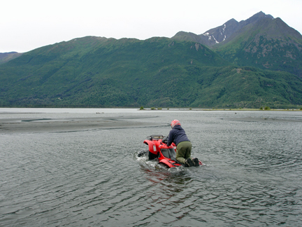 the guide kneeling & driving across the deep river