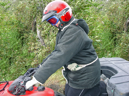 Karen Duquette kneeling on the seat of her ATV 