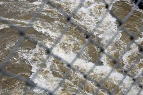 looking at the river through the side fencing on the bridge