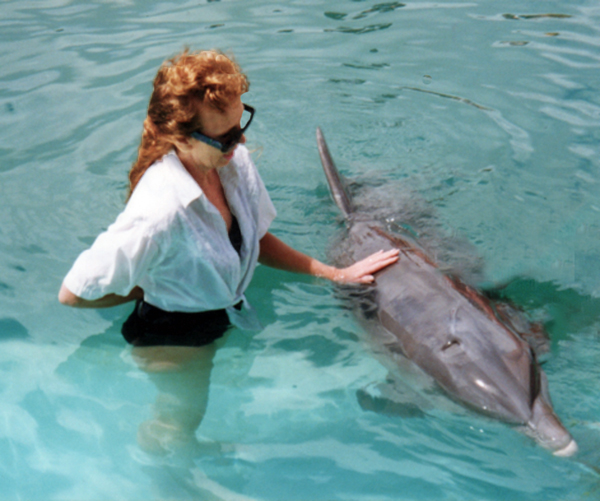 Karen Duquette touching a dolphin