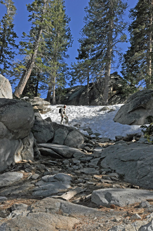 Lee climbs a small rocky hill that has patches of icy snow