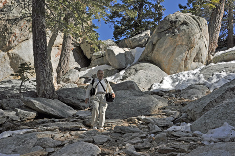 Lee climbs a small rocky hill that has patches of icy snow
