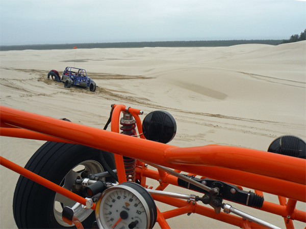 The blue dune buggy is stuck in the sand