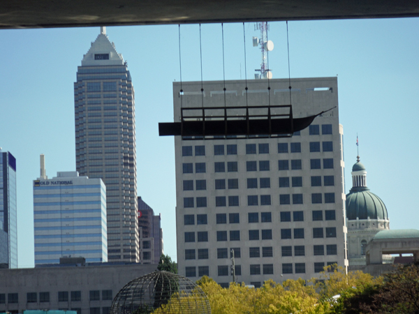 A small boat hanging from the underside of a bridge